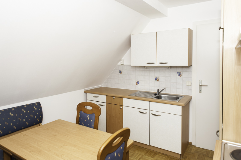 Küchenblock mit Spüle und unterschränken sowie Hochschränken, Esstisch mit Stühlen